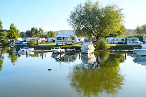 Camping site on a lake with caravans and boats.